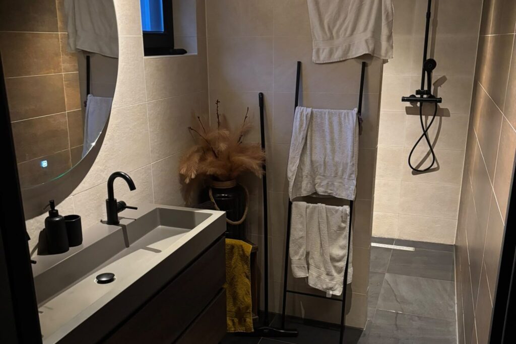 Badkamer met ronde spiegel en zwarte kranen