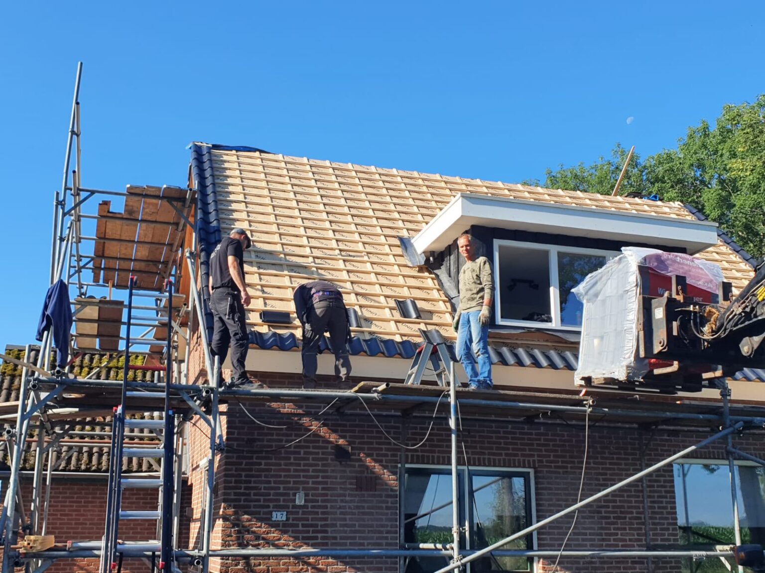 Vakmensen van Pathon aan het werk op het dak van de woning in De Glind