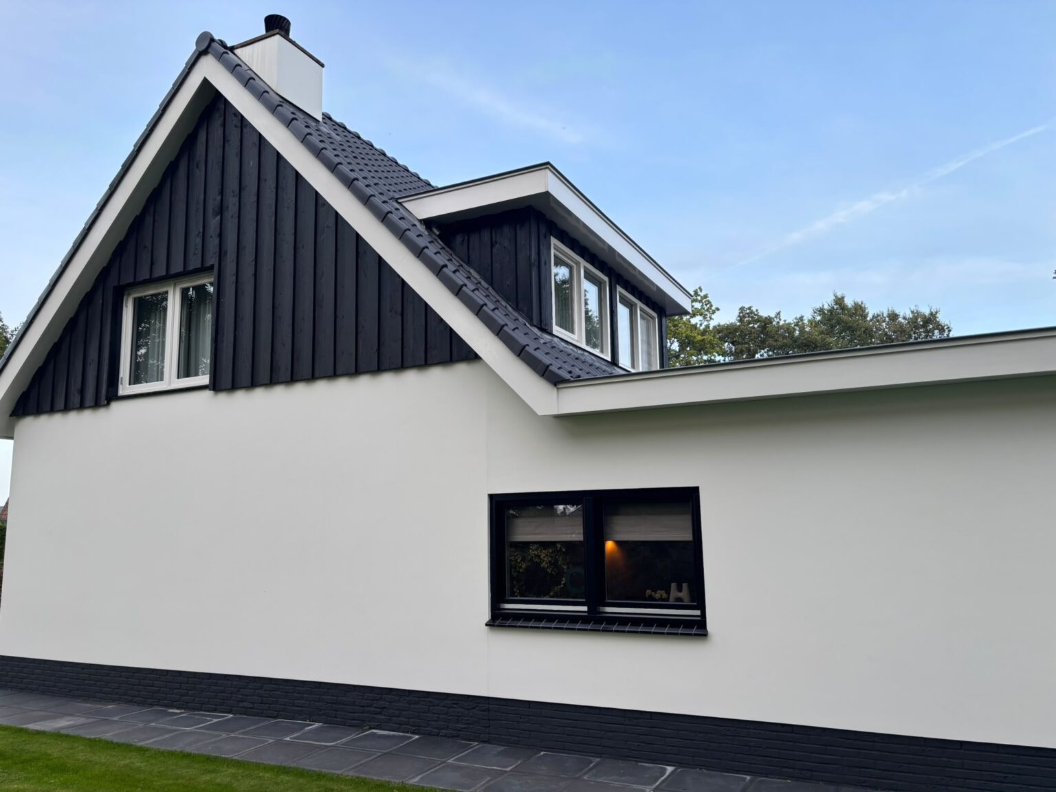 Gerenoveerde gevel in wit stucwerk met donkere houten delen