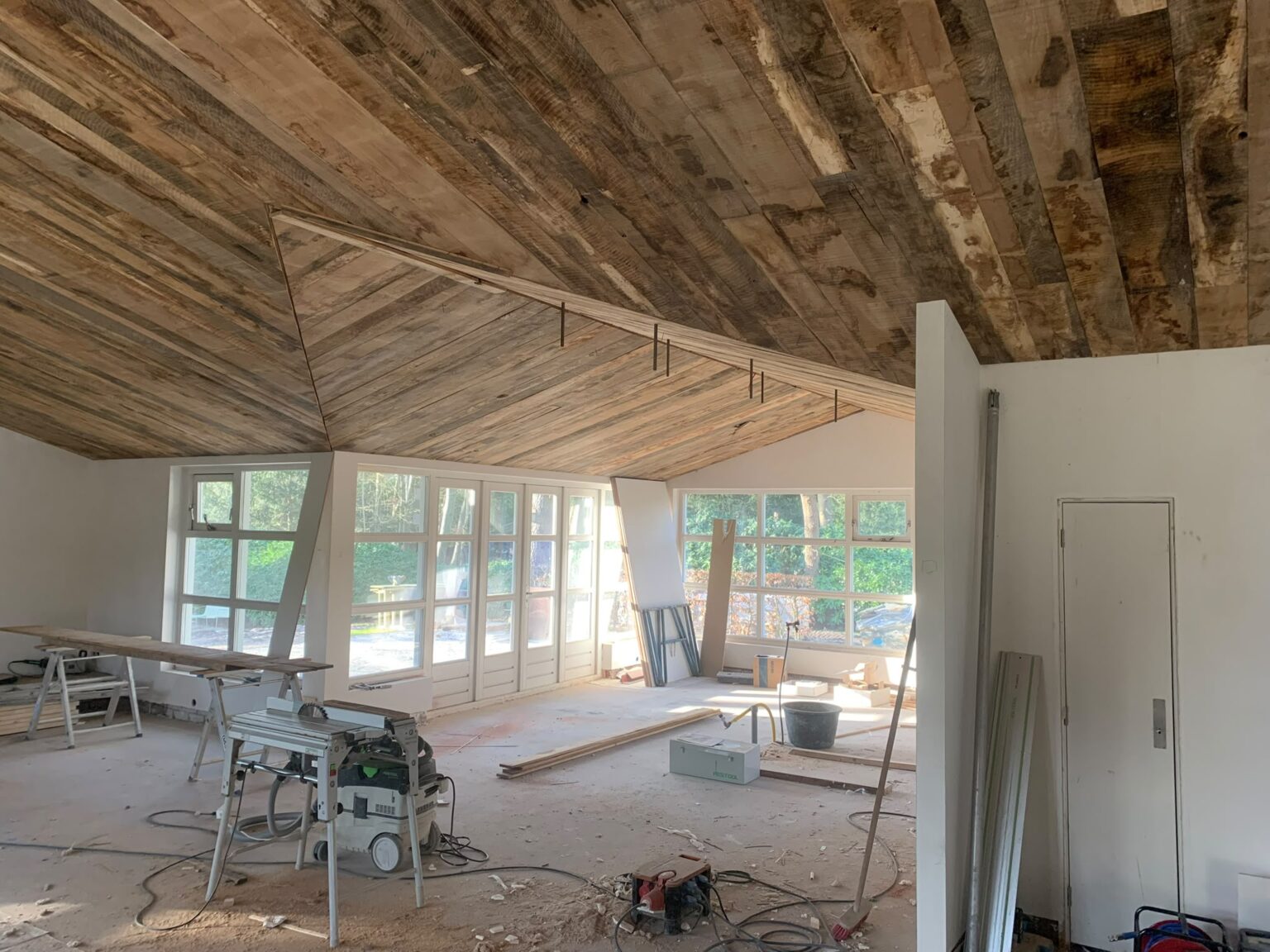 Houten plafond in verstek in een woonruimte met veel glas