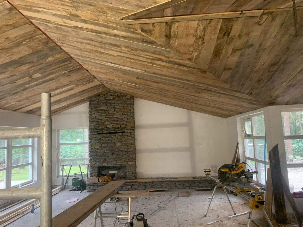 Natuurstenen haardwand onder een houten plafond